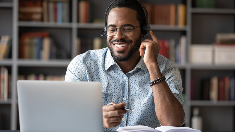 Happy Biracial Male In Headset Studying On Modern Laptop