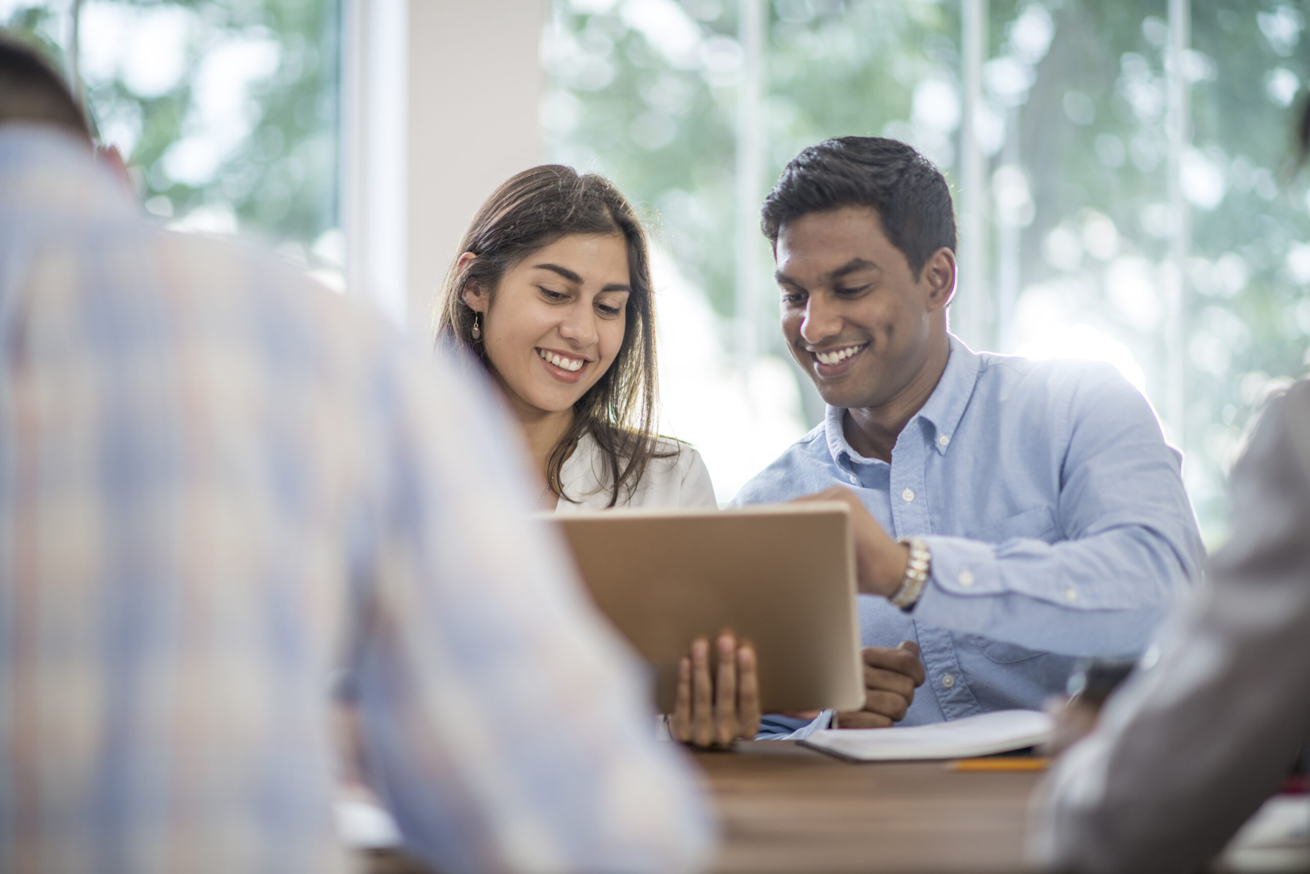 A multi-ethnic group of businessmen and businesswomen are working together in the boardroom to discuss new business concepts and ideas. They are developing new strategies in the corporate workplace.