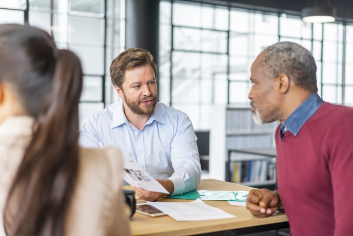 Male Colleagues Discussing Over Document At Office