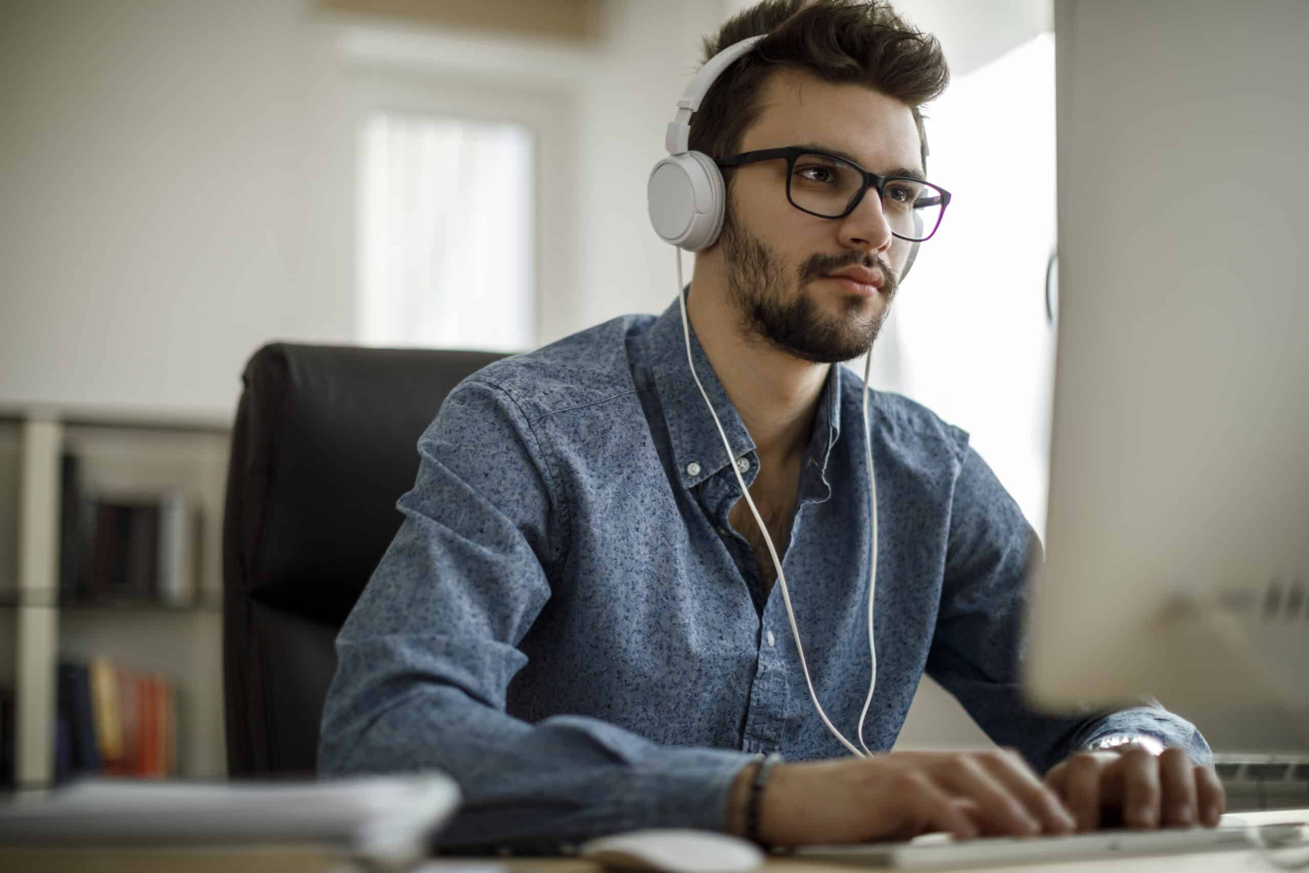 Young businessman enjoying music and working on computer