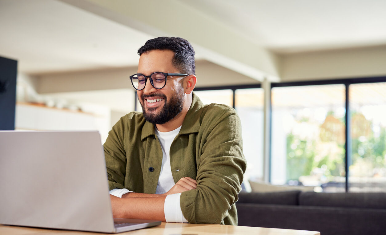 Happy hispanic man working on laptop at home